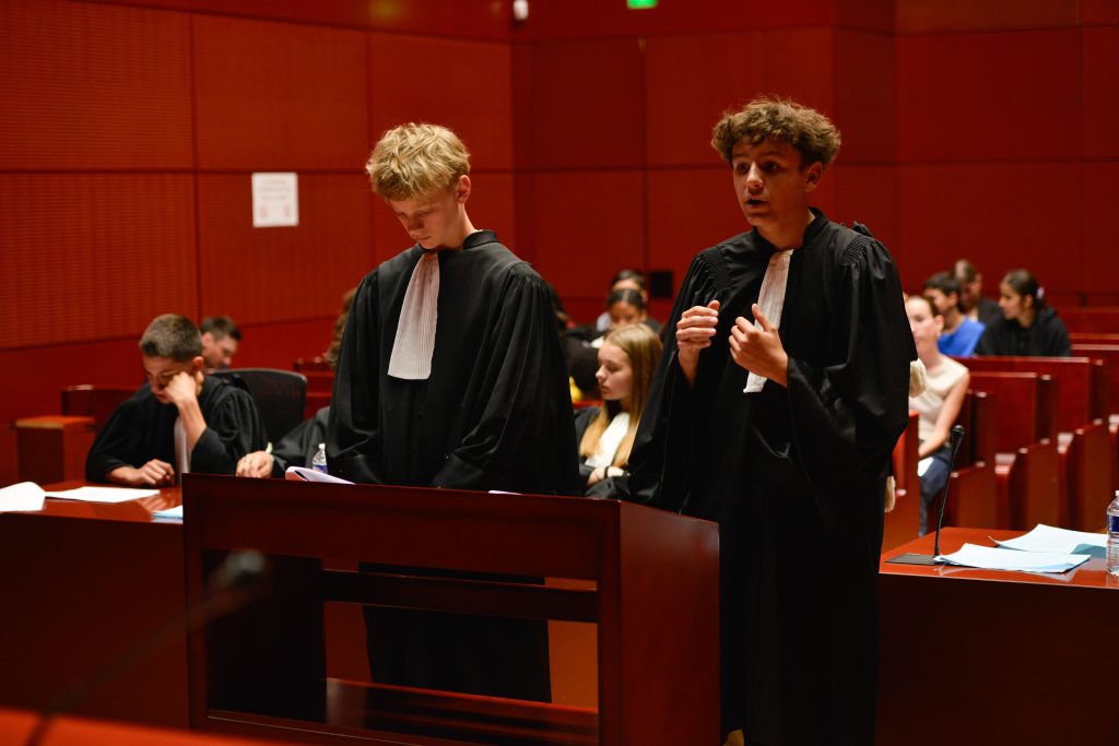Photo de deux jeunes collégiens en tenue d'avocat dans un tribunal à Nantes, rejouant un procès fictif avec l'association Ose ton Futur